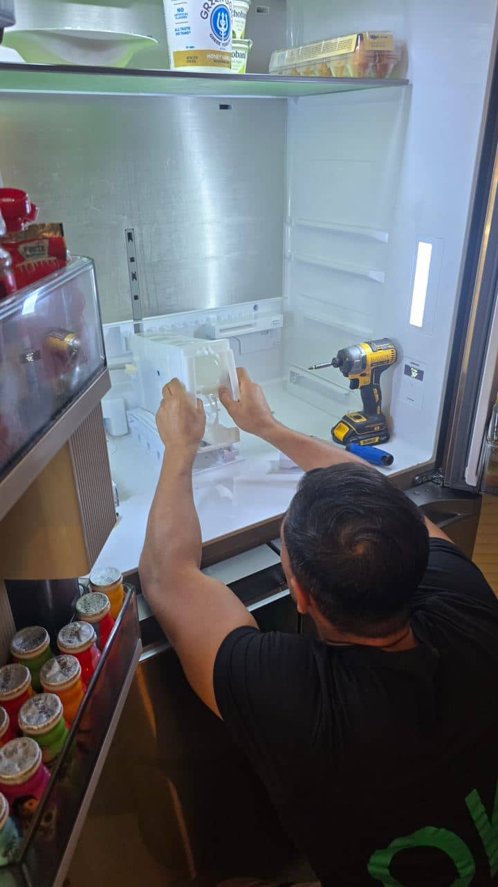 OK Appliance Repair technician working inside a refrigerator